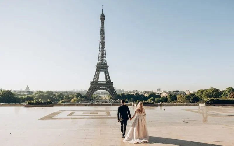 Dressed up couple holding hands in front of Eiffel Tower